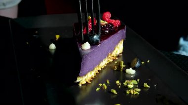 Dikey videoda leylak rengi lezzetli çilekli kek ve çatallı üzümlü çikolatalı kek var. Beyaz ekşi krema kreması. Yüksek kalite 4k görüntü