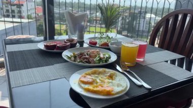 Masa suyu yumurtaları salata kahvaltısı lüks otel ekipmanlarıyla dağ manzaralı ahşap balkonda. Yüksek kalite 4k görüntü