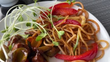 Ahşap zemin üzerinde beyaz bir tabakta deniz mahsulü ile udon karıştırılmış erişteler. Üst Manzara. Yüksek kalite 4k görüntü