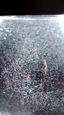 Temiz içme suyu siyah arka plandaki bir bardağa dökülür. Bir bardak suda gökkuşağı