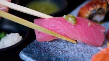 Orkinos yakın plan yemek çubukları yanında küçük bir seramik bardakla ahşap bir tahtanın üzerinde suşi tutuyor. Yüksek kalite 4k görüntü