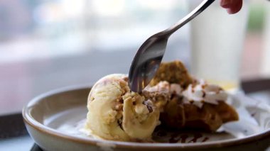 Kahvaltıda ya da tatlıda tatlı yemek, Belçika waffle 'ında dondurma kepçesi, birisi çay kaşığıyla bir parça dondurmayı ikinci kez alıyor. İkinci waffle 'da böğürtlen görebilirsiniz. 4k 
