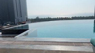 Sakin çatı sonsuz havuzu çarpıcı bir günbatımının canlı renklerini yansıtır, sakin ve huzurlu bir atmosfer yaratır rahatlama ve lüks seyahat için mükemmel, havuz üzerinde huzurlu bir gün batımı.