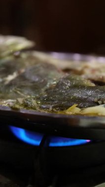 Kadınların el yapımı yemekleri fırının üstünde kızartma tavasında yakın plan çekimleri. Asya tencerede balık pişiriyor.