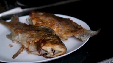 Lezzetli kızarmış balık ya da balık soğan, domates ve limonla birlikte siyah bir tabakta kızarır. Hint usulü baharatlı Kerala balığı ahşap bir masada kızarır. Limon ızgara balığın üzerine sıkılmış. Yüksek kalite 4k görüntü