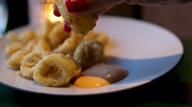 Lezzetli bir sosla servis edilen kızarmış kalamarının tadını çıkarın. Kızarmış kalamar, kremalı sos ve lezzetli bir dilim limonla servis edilir.. 