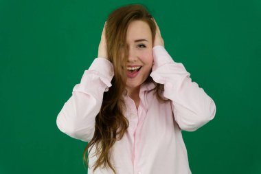 Mutlu ve heyecanlı. Mavi stüdyo arka planında poz veren genç, gülümseyen, günlük kıyafetler içindeki güzel bir kız portresi. Gençlik kavramı, güzellik, moda, yaşam tarzı, duygular, yüz ifadesi. 