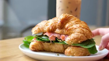 Yakası çok güzel olan tanınmayan bir kadın bir kafede kahvaltıda yanında kruvasan sandviçle haşlanmış domuz eti yiyor ve kahve içiyor. 4K, yavaş çekim, yakın çekim. Yüksek kalite 4k görüntü