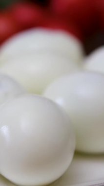 Birisi haşlanmış yumurtanın kabuğunu kırıyor, kabuğunu soyuyor ve beyaz bir tabağa yerleştiriyor. Yüksek kalite 4k görüntü