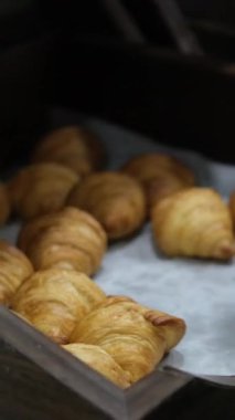 Kruvasan ahşap tepsi servis masası, kruvasan sandviçler ve ahşap tepsilerde sıralanmış, yanında servis için hazır beyaz tabaklar. Yüksek kalite 4k görüntü