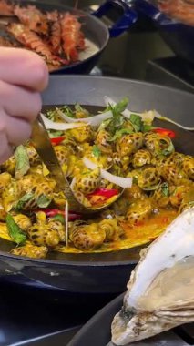 Cruiser 'da büyük bir balık yemeğinin servis edildiği açık büfe sahnesi. Balık, aşındırıcı bir tabağa konmuş sebze ve sosla süslenir. Birisi balıklara maşa veriyor. 