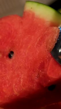 Karpuz kesiyorum. Kesme tahtasındaki karpuz dilimleri. Meyvenin kırmızı posası. Güneşli bir günde masada yemek. Yüksek kalite