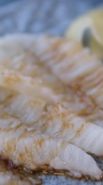 Ahşap tahtadan ızgara beyaz uskumru filetosu alan bir çatalın yakın çekimi. Yüksek kalite 4k görüntü