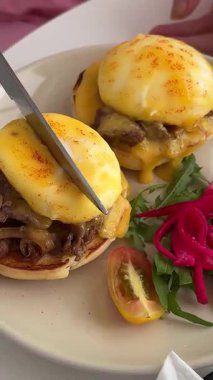 Yeşil tabakta kızarmış yumurta ve ekmek yemek. Yakın plan. Bakış açısı. Renkli arka plan. Tostlu geleneksel kahvaltı. Güneşli bir gün. Yumurtalı Benedict sandviçi.