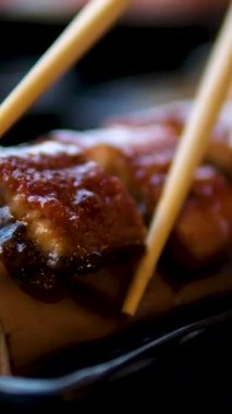 Farklı rulo, nigiri, maki, gunkan içeren düz bir tabakta süslü siyah suşi. Japon ulusal mutfağı yakın plan. Yemek çubukları füme yılan balığı.