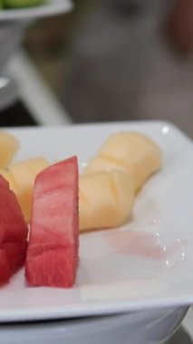 Karpuz kesiyorum. Kesme tahtasındaki karpuz dilimleri. Meyvenin kırmızı posası. Güneşli bir günde masada yemek. Yüksek kalite 4k görüntü. 