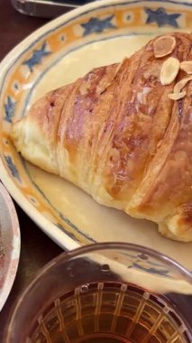 Masanın üzerinde lezzetli bir Vietnam yumurtası kahvesi ve bir kruvasan var, ayrıca bir bardak çay, kız tablet üzerinde çalışıyor. Yüksek kalite 4k görüntü