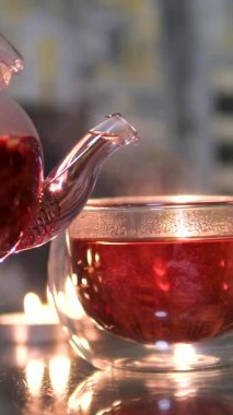 Mutfaktaki ahşap masada sıcak çayla duran kupa. Küçük bir kaşıkla bir el şeffaf bir fincanda çay karıştırır. Çay poşetiyle kaşığı yavaş çekimde karıştırmak. - Evet. Yüksek kalite 4k görüntü