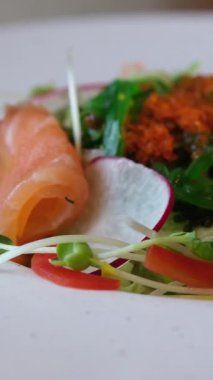 Ellerinde çatal bıçak takımı, somonla salata dilimleme, restoranda lezzetli bir öğle yemeği. Yüksek kalite 4k görüntü