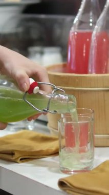 Masanın üzerinde çeşitli içecekler var. Ahşap küvetler, karpuz, yeşil kereviz ve salatalık dişilerin elleri bardağa detoks döküyor. Yüksek kalite 4k görüntü