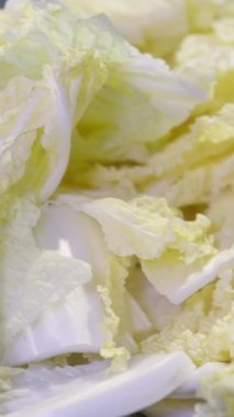 Tahta bir kesim tahtasının üzerinde, yanında beyaz bir kase ve cam bir masanın üzerinde bir tabak mısır gevreği ile Napa lahanası doğramak. Yüksek kalite 4k görüntü