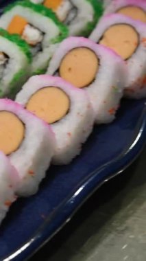 Salatalık dilimleri ve ton balıklı saşimi ile renklendirilmiş suşi ruloları. Yüksek kalite 4k görüntü