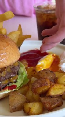Soda ve patates kızartmasıyla servis edilen taze lezzetli hamburger. Kız hamburgeri aldı.