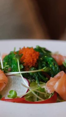 Ellerinde çatal bıçak takımı, somonla salata dilimleme, restoranda lezzetli bir öğle yemeği. Yüksek kalite 4k görüntü