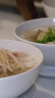 Çorbaya taze soğan ekleyin. Taze Vietnam pilavı, taze bitkiler, limon suyu ve fasulye filizi. Kadın, otantik Vietnam lezzetlerini arttıran malzemeler ekliyor. 