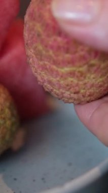 Genç bir kız bir liçi meyvesini soymaya çalışır. Taze liçi yiyen kız. Bir kadın ve liçi meyvesi. Meyve yeme kavramları. Yakın çekim 4K videosu. - Evet. Yüksek kalite 4k görüntü