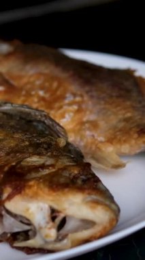 Lezzetli kızarmış balık ya da balık soğan, domates ve limonla birlikte siyah bir tabakta kızarır. Hint usulü baharatlı Kerala balığı ahşap bir masada kızarır. Limon ızgara balığın üzerine sıkılmış. Yüksek kalite 4k görüntü