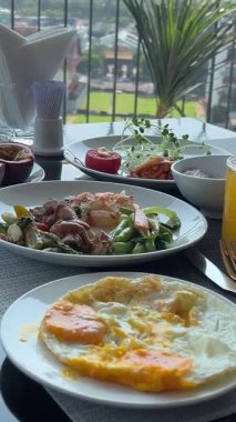 Masa suyu yumurtaları salata kahvaltısı lüks otel ekipmanlarıyla dağ manzaralı ahşap balkonda. Yüksek kalite 4k görüntü