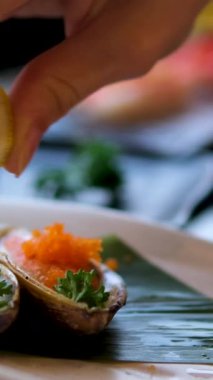 Bir kafede istiridyenin içine limon sıkıştıran genç bir kadın. İstiridye limonu sıkma