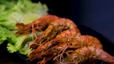 Izgara karides ve taze sebzeler ahşap masadaki siyah taş tabakta servis ediliyor. Yüksek kalite fotoğraf