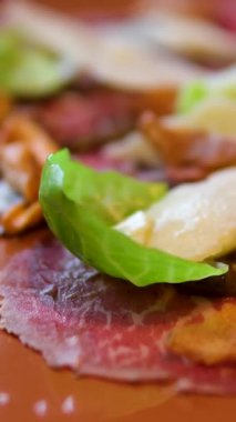 Parmesanlı biftek carpaccio, vişneli domates, kırmızı soğan ve roka. Yüksek kalite 4k görüntü