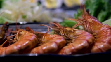 Izgara karides ve taze sebzeler ahşap masadaki siyah taş tabakta servis ediliyor. Yüksek kalite fotoğraf