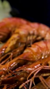 Izgara karides ve taze sebzeler ahşap masadaki siyah taş tabakta servis ediliyor. Yüksek kalite fotoğraf