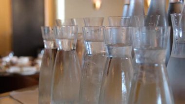 Bir restoranda birkaç sürahi soğuk su bardağa yavaş çekimde, sıvı olarak dökülür. Yüksek kalite 4k görüntü