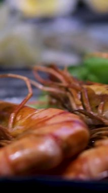 Izgara karides ve taze sebzeler ahşap masadaki siyah taş tabakta servis ediliyor. Yüksek kalite fotoğraf