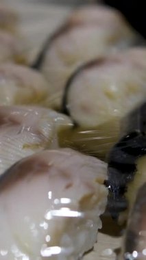 Plastik filme sarılı ton balığı filetoları ve biftekler, taze ve kaliteyi vurgulayan, yeşil yapraklarla süslenmiş, balık pazarındaki metal tepsilerde sergileniyor. Yüksek kalite 4k görüntü