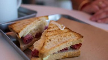 Lezzetli bir pastırma, peynir ve yumurtalı sandviç yiyorum. Yüksek kalite 4k görüntü