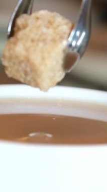 Yavaş Hareketli El, şeker küpünü sade kahveye döküyor. Şeker kahve fincanına düşer. Kafein Bağımlısı Hurda Yiyecekler. Sağlıksız Yeme, Diyabet, Obezite, Kalp Hastalığı Konsepti.