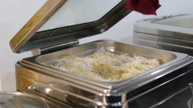 İnsanlar uzun bir masanın etrafında iki sıra halinde alfredo ve marinara sosunun yanı sıra pirinç, sebze ve tavuk içeren makarna büfesiyle yemek servisi yapıyorlar. Yüksek kalite 4k görüntü