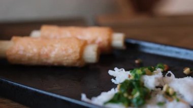 Yemek çubuklarının yakın çekimi siyah tabakta garnitürlü pirinç erişteleri topluyor. Yüksek kalite 4k görüntü