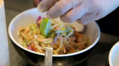 Sezar Salatası 'nın hazırladığı taze salataya tavuk parçaları koyan eller. Salata kasesi hazırlanıyor.