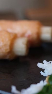 Yemek çubuklarının yakın çekimi siyah tabakta garnitürlü pirinç erişteleri topluyor. Yüksek kalite 4k görüntü