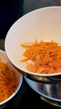 El kamerasıyla seçilmiş odak fotoğrafı, kadının elleri tahta kesme tahtasıyla havuç kesiyor, Asyalı kadın salata rulosu yapmak için taze sebze hazırlıyor. - Salata kasesi hazırlanıyor.