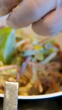 Sezar Salatası 'nın hazırladığı taze salataya tavuk parçaları koyan eller. Salata kasesi hazırlanıyor.