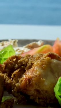 Çıtır Tavuk Salatası: Çıtır çıtır ve sağlıklı bir yemek, taze karışık yeşillikler, doğranmış kırmızı lahana ve havuçlardan oluşan bir yatakta servis edilen kızarmış tavuk göğsü dilimleri. Yüksek kalite 4k 