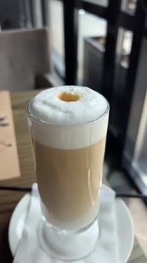 Sıcak bir kafe ortamında katmanlı kahve içmenin tadını çıkarıyorum. Yüksek kalite 4k görüntü